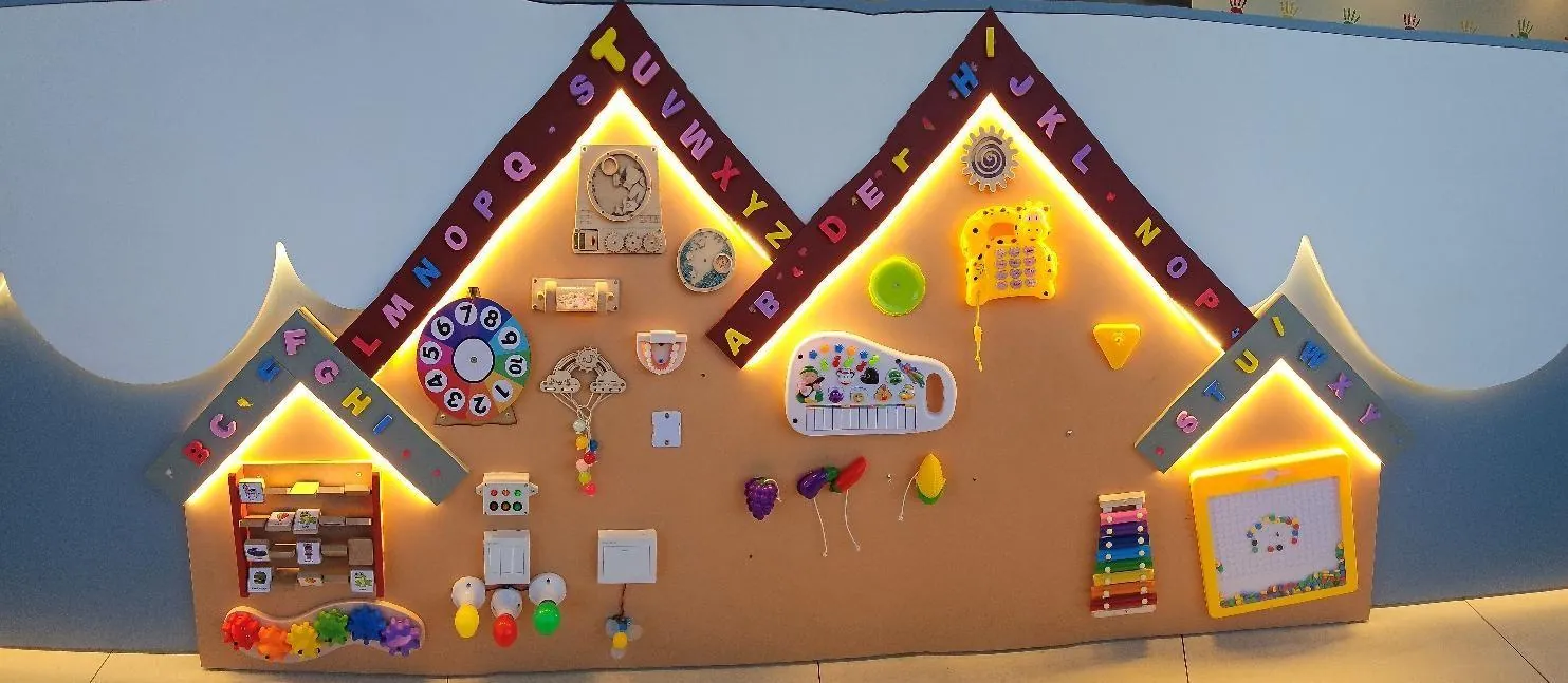 Balcão sensorial da recepção, com painéis em formato de casinha, instrumentos e brinquedos de estímulo